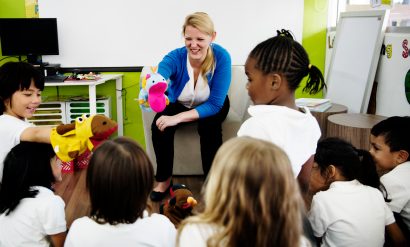 Students sat on the carpet with their teacher telling a story using puppets