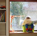 Small child sitting in a plastic box reading a book