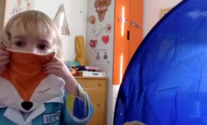 A young girl named Olivia participating in a playful Zoom interview as part of Kelsey's research. She is using a fox shaped cushion as a pretend face mask.